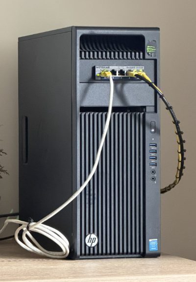 The Monolith: an HP Z440 tower workstation with a NETGEAR ProSAFE switch fitted into its front drive bay, patched in with yellow ethernet cables.